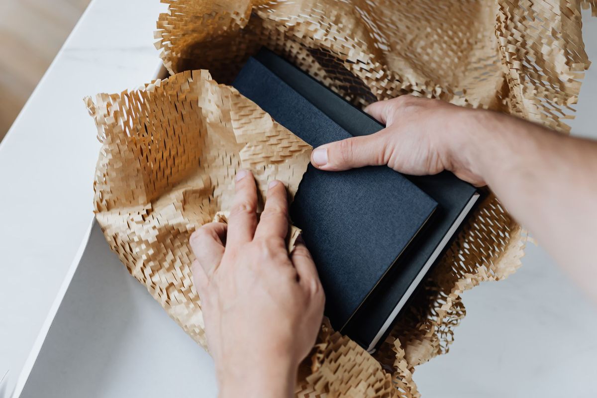 Hands wrapping notebooks in honeycomb kraft paper